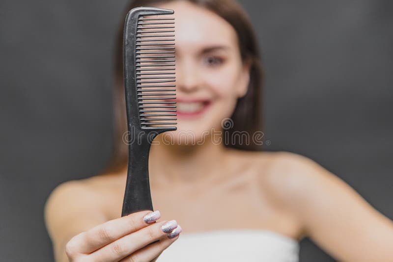 Vue frontale d'une belle jeune fille dans un rasoir blanc Peign?e du cheveu Plan rapproché d'un peigne sur le fond trouble d'une photo libre de droits Vue frontale d'une belle jeune fille dans un rasoir blanc Peign?e du cheveu Plan rapproché d'un peigne sur le fond trouble d'une photo libre de droits