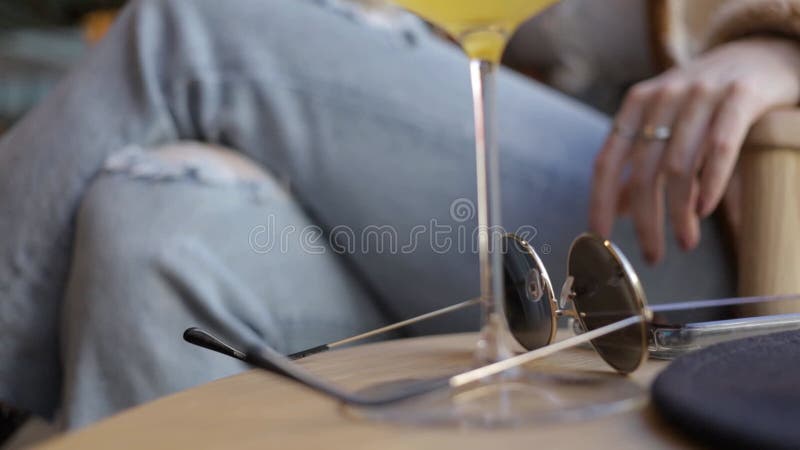 Vue haute étroite de la main d'une femme avec des lunettes de soleil et le chapeau noir sur la table basse clips vidéos