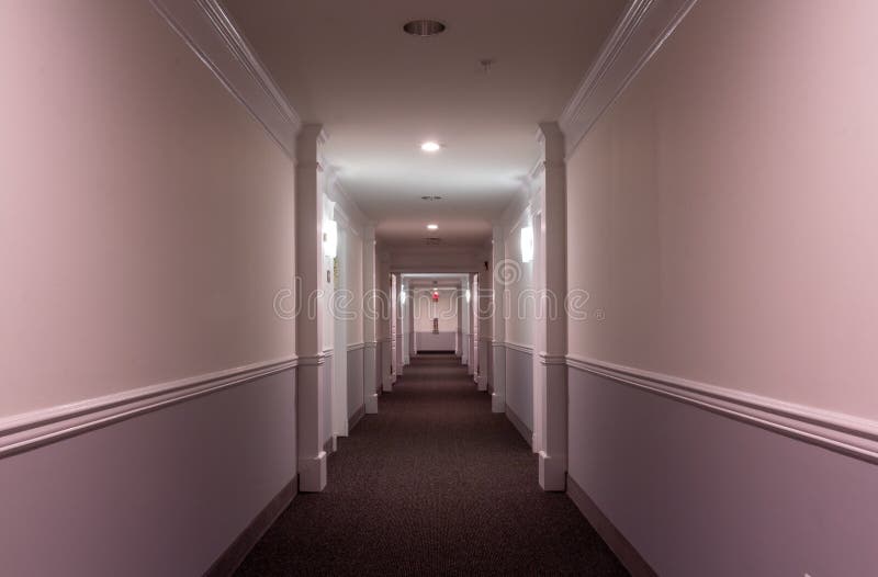 Vue intérieure horizontale sur le couloir d'un immeuble d'appartements moderne avec des entrées en arc de cercle moulant éclairage