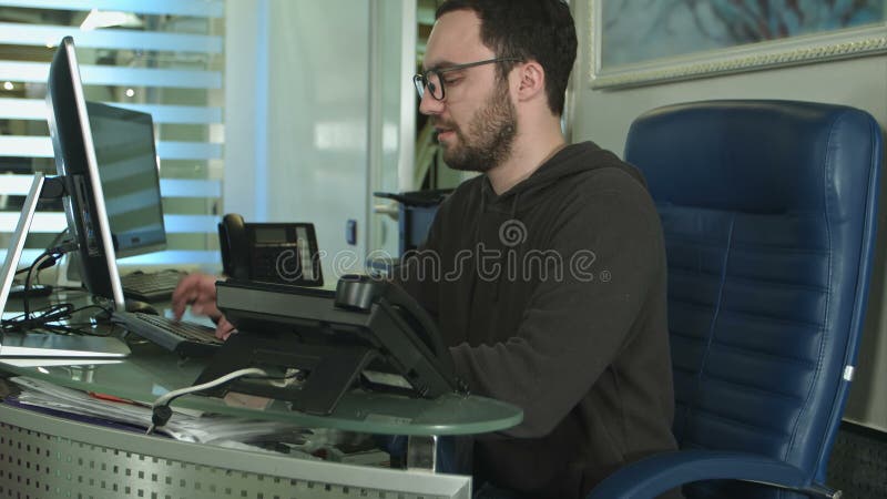 Vue latérale d'un employé de bureau masculin travaillant sur un ordinateur dans un bureau lumineux banque de vidéos