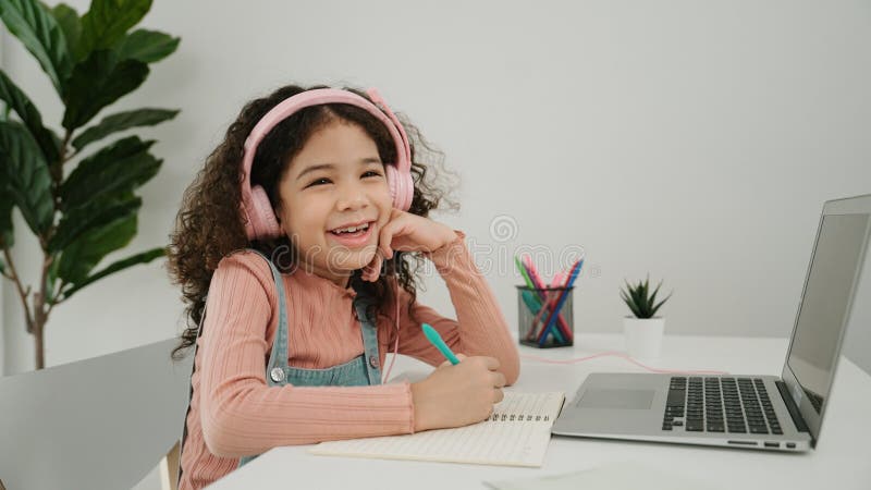 Vue latérale de la fille avec casque faire les devoirs et regarder la caméra. pédagogie. photo stock