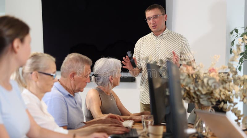 Vue latérale des personnes âgées en cours d'informatique à la maison de soins infirmiers banque de vidéos