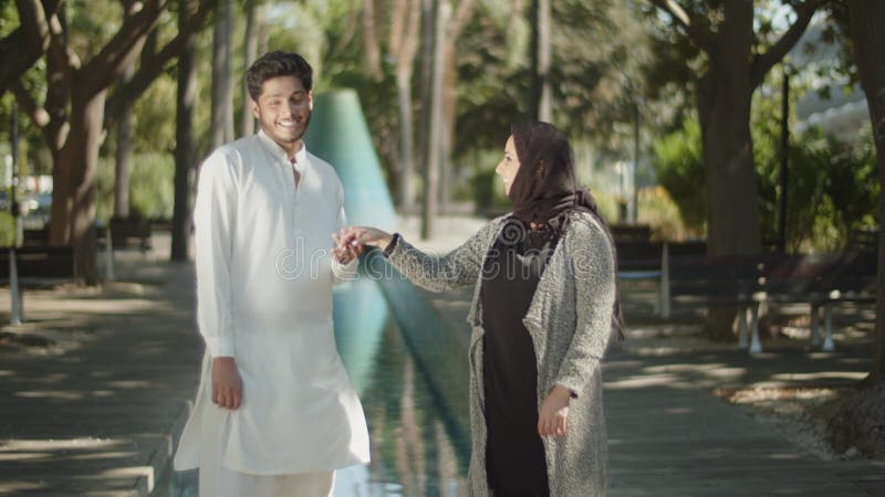 Vue latérale du jeune couple musulman tenant la main dans le parc. clips vidéos