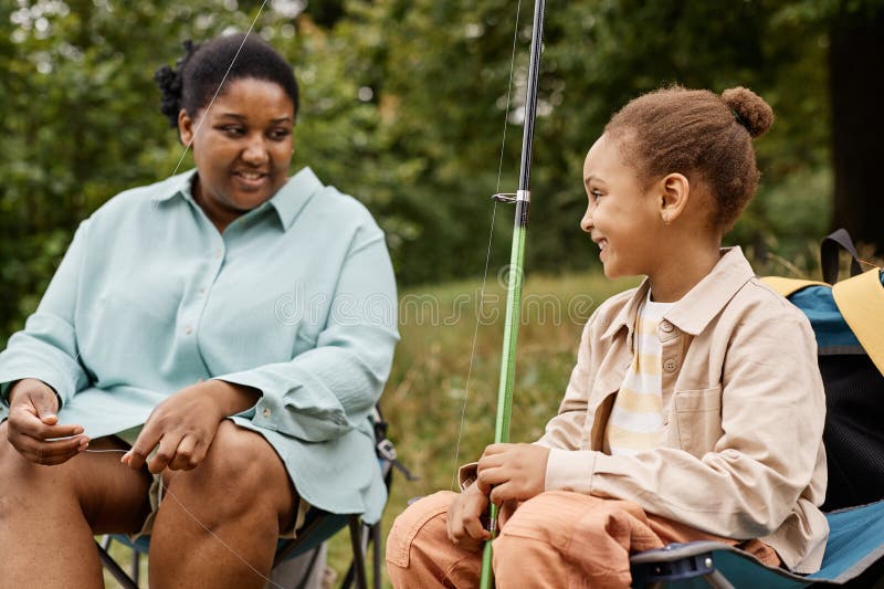 Vue latérale petite fille souriant joyeusement tout en appréciant la sortie de pêche avec les parents photographie stock libre de droits