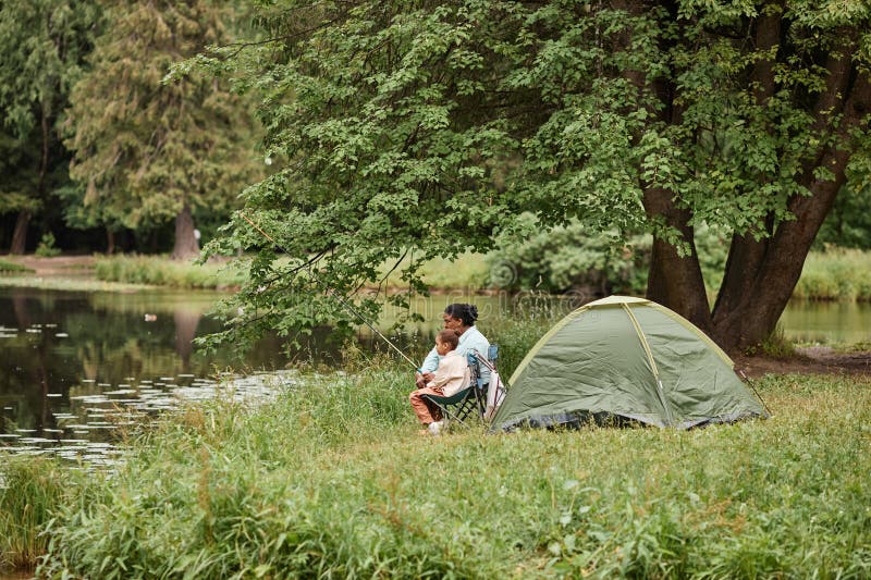 Vue panoramique sur la mère et la fille campant ensemble à l'extérieur et pêchant photos stock