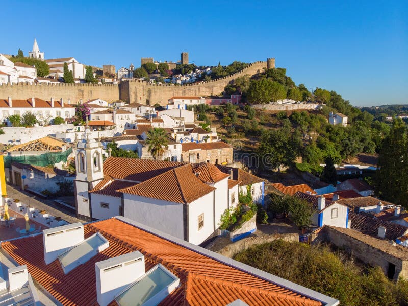 Vue scénique des toits carrelés rouges de maisons blanches, et château de mur de forteresse Village d'Obidos photo stock Vue scénique des toits carrelés rouges de maisons blanches, et château de mur de forteresse Village d'Obidos photo stock
