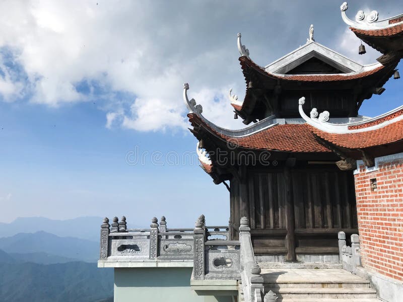 Vue stupéfiante de toit de tuile de temple bouddhiste traditionnel sur les montagnes et le fond bleus de ciel photos stock Vue stupéfiante de toit de tuile de temple bouddhiste traditionnel sur les montagnes et le fond bleus de ciel photos stock