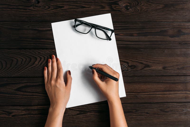 Vue sup?rieure des mains des femmes, pr?te ? ?crire quelque chose sur un morceau de papier vide se trouvant sur une table en bois image libre de droits Vue sup?rieure des mains des femmes, pr?te ? ?crire quelque chose sur un morceau de papier vide se trouvant sur une table en bois image libre de droits