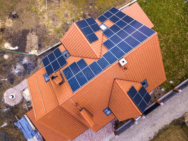 Aerial top view of new modern residential house cottage with blue shiny solar photo voltaic panels system on roof. Renewable ecological green energy production concept. Aerial top view of new modern residential house cottage with blue shiny solar photo voltaic panels system on roof. Renewable ecological green energy production concept