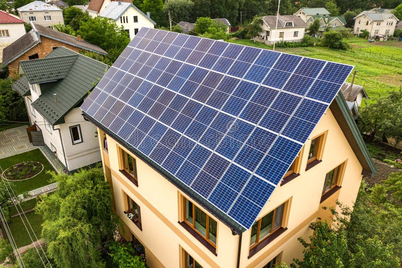 Aerial top view of new modern residential house cottage with blue shiny solar photo voltaic panels system on roof. Renewable ecological green energy production concept. Aerial top view of new modern residential house cottage with blue shiny solar photo voltaic panels system on roof. Renewable ecological green energy production concept.