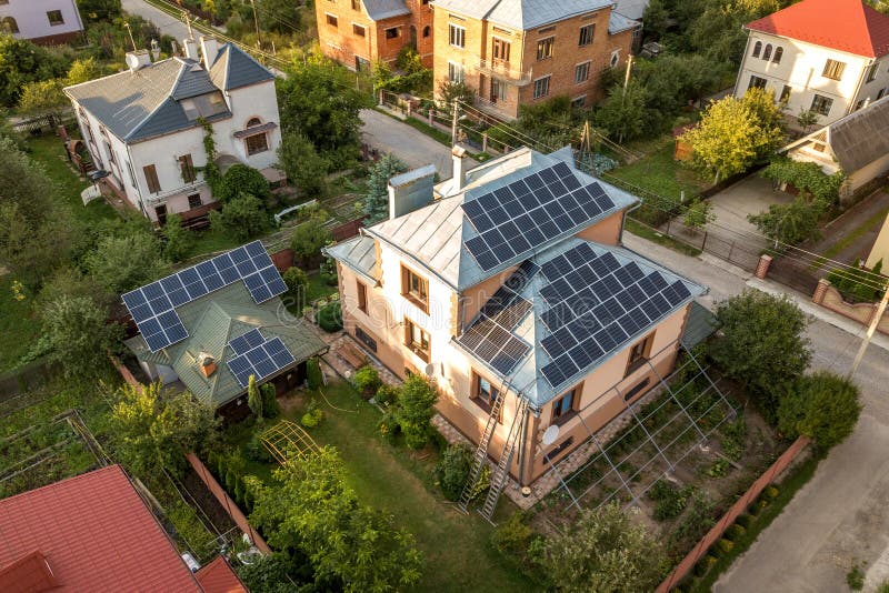 Aerial top view of new modern residential house cottage with blue shiny solar photo voltaic panels system on roof. Renewable ecological green energy production concept. Aerial top view of new modern residential house cottage with blue shiny solar photo voltaic panels system on roof. Renewable ecological green energy production concept.