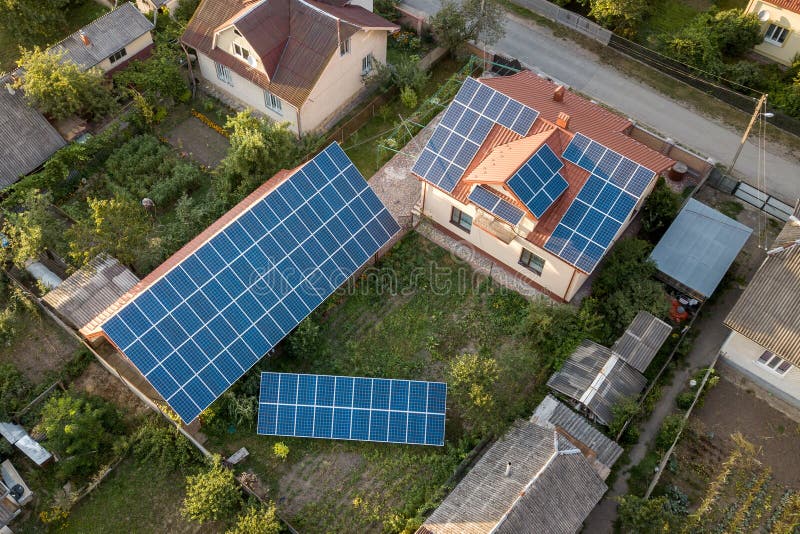 Aerial top view of new modern residential house cottage with blue shiny solar photo voltaic panels system on roof. Renewable ecological green energy production concept. Aerial top view of new modern residential house cottage with blue shiny solar photo voltaic panels system on roof. Renewable ecological green energy production concept.