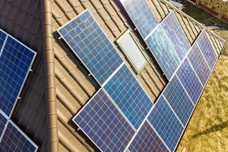 Aerial top view of new modern residential house cottage with blue shiny solar photo voltaic panels system on roof. Renewable ecological green energy production concept. Aerial top view of new modern residential house cottage with blue shiny solar photo voltaic panels system on roof. Renewable ecological green energy production concept.