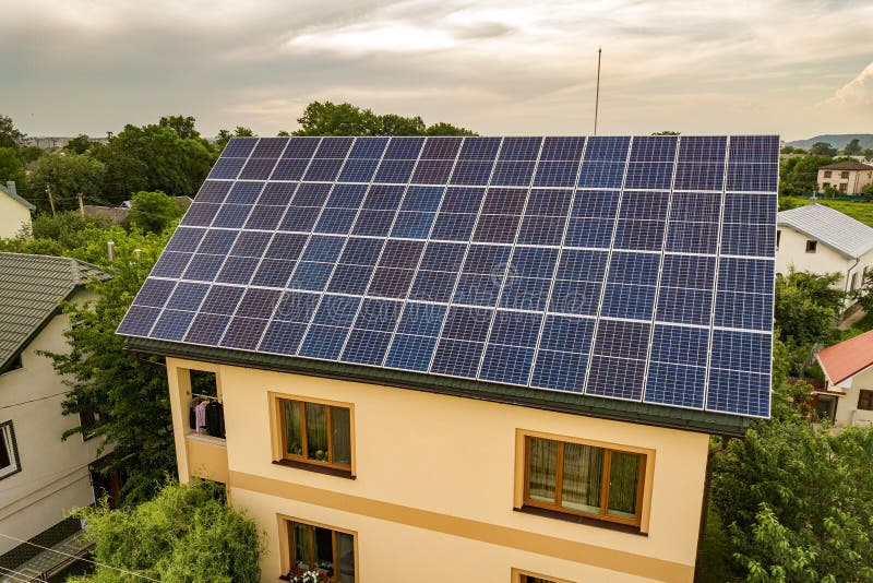 Aerial top view of new modern residential house cottage with blue shiny solar photo voltaic panels system on roof. Renewable ecological green energy production concept. Aerial top view of new modern residential house cottage with blue shiny solar photo voltaic panels system on roof. Renewable ecological green energy production concept.