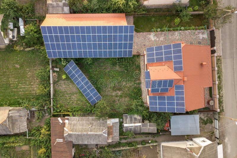 Aerial top view of new modern residential house cottage with blue shiny solar photo voltaic panels system on roof. Renewable ecological green energy production concept. Aerial top view of new modern residential house cottage with blue shiny solar photo voltaic panels system on roof. Renewable ecological green energy production concept.