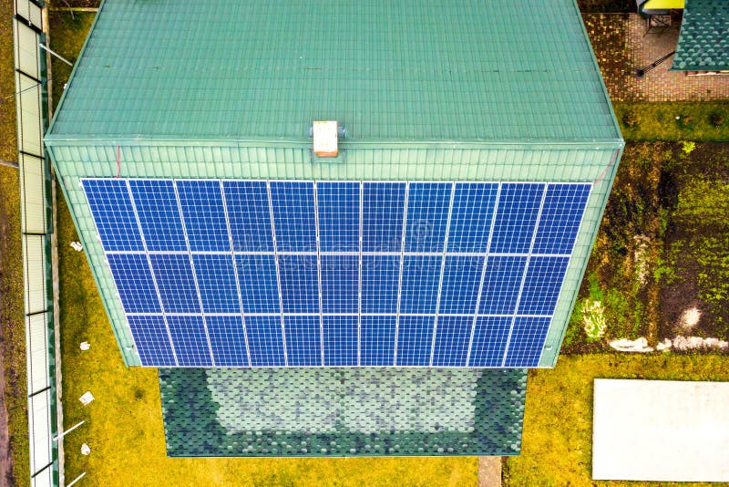 Aerial top view of new modern residential house cottage with blue shiny solar photo voltaic panels system on roof. Renewable ecological green energy production concept. Aerial top view of new modern residential house cottage with blue shiny solar photo voltaic panels system on roof. Renewable ecological green energy production concept.