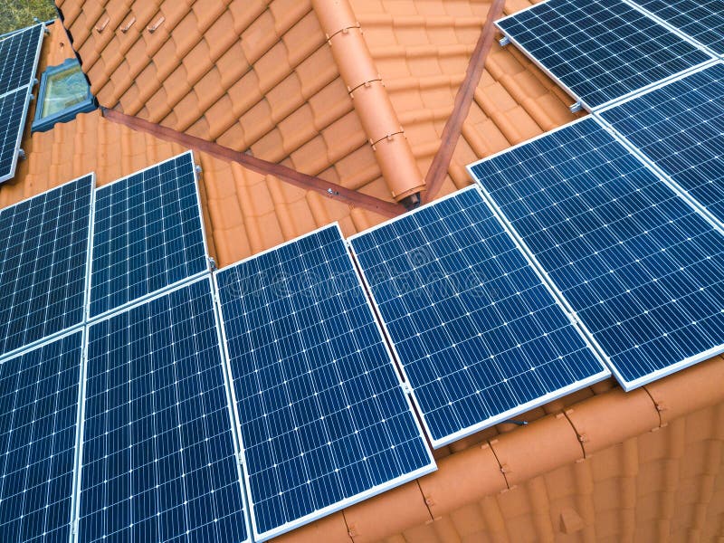 Aerial top view of new modern residential house cottage with blue shiny solar photo voltaic panels system on roof. Renewable ecological green energy production concept. Aerial top view of new modern residential house cottage with blue shiny solar photo voltaic panels system on roof. Renewable ecological green energy production concept