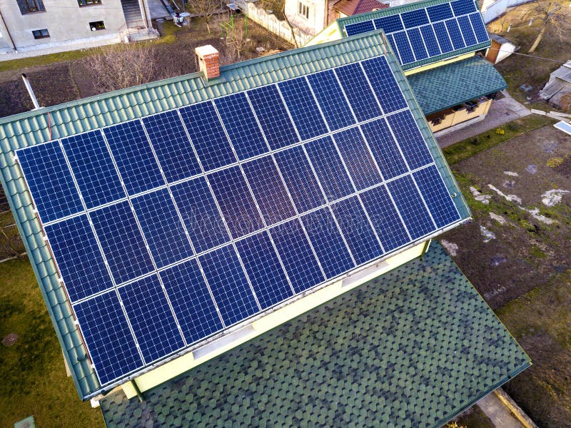 Aerial top view of new modern residential house cottage with blue shiny solar photo voltaic panels system on roof. Renewable ecological green energy production concept. Aerial top view of new modern residential house cottage with blue shiny solar photo voltaic panels system on roof. Renewable ecological green energy production concept