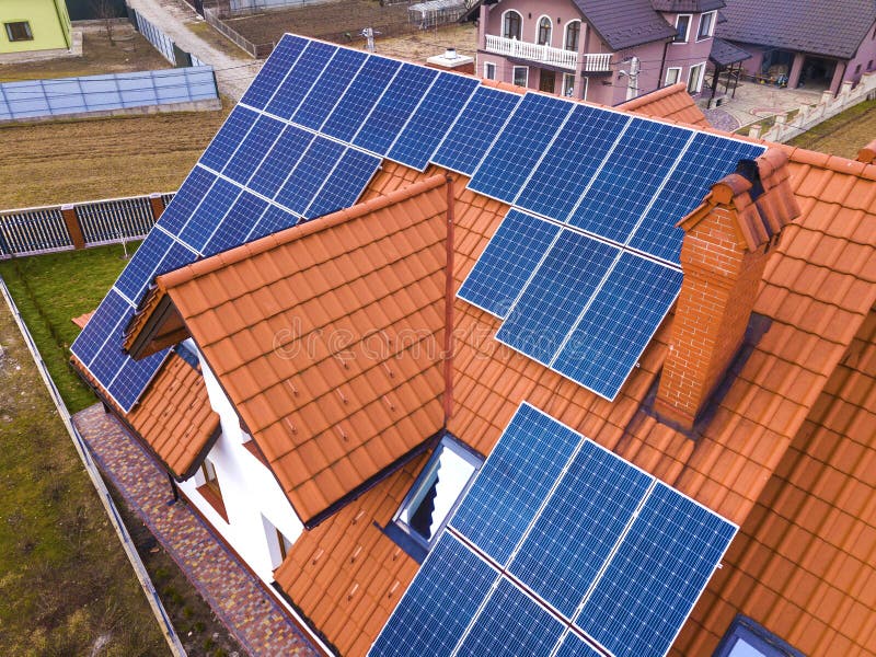 Aerial top view of new modern residential house cottage with blue shiny solar photo voltaic panels system on roof. Renewable ecological green energy production concept. Aerial top view of new modern residential house cottage with blue shiny solar photo voltaic panels system on roof. Renewable ecological green energy production concept