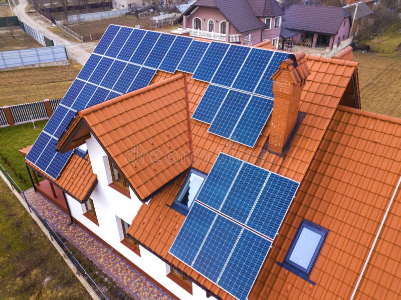 Aerial top view of new modern residential house cottage with blue shiny solar photo voltaic panels system on roof. Renewable ecological green energy production concept. Aerial top view of new modern residential house cottage with blue shiny solar photo voltaic panels system on roof. Renewable ecological green energy production concept