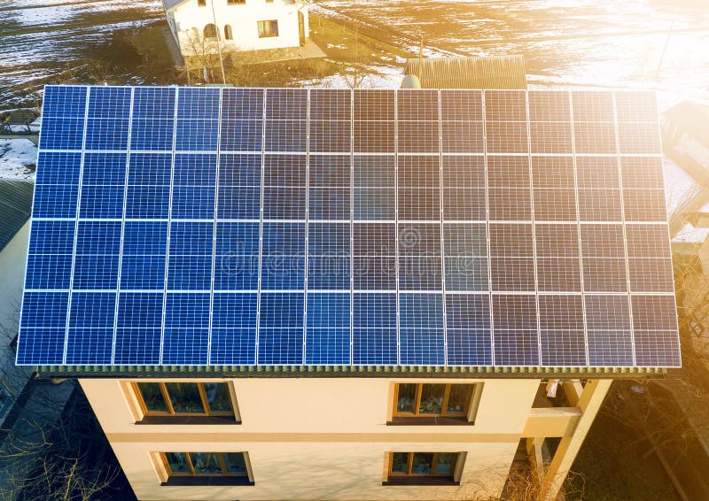 Aerial top view of new modern residential two story house cottage with blue shiny solar photo voltaic panels system on roof. Renewable ecological green energy production concept. Aerial top view of new modern residential two story house cottage with blue shiny solar photo voltaic panels system on roof. Renewable ecological green energy production concept