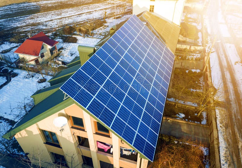 Aerial top view of new modern residential two story house cottage with blue shiny solar photo voltaic panels system on roof. Renewable ecological green energy production concept. Aerial top view of new modern residential two story house cottage with blue shiny solar photo voltaic panels system on roof. Renewable ecological green energy production concept