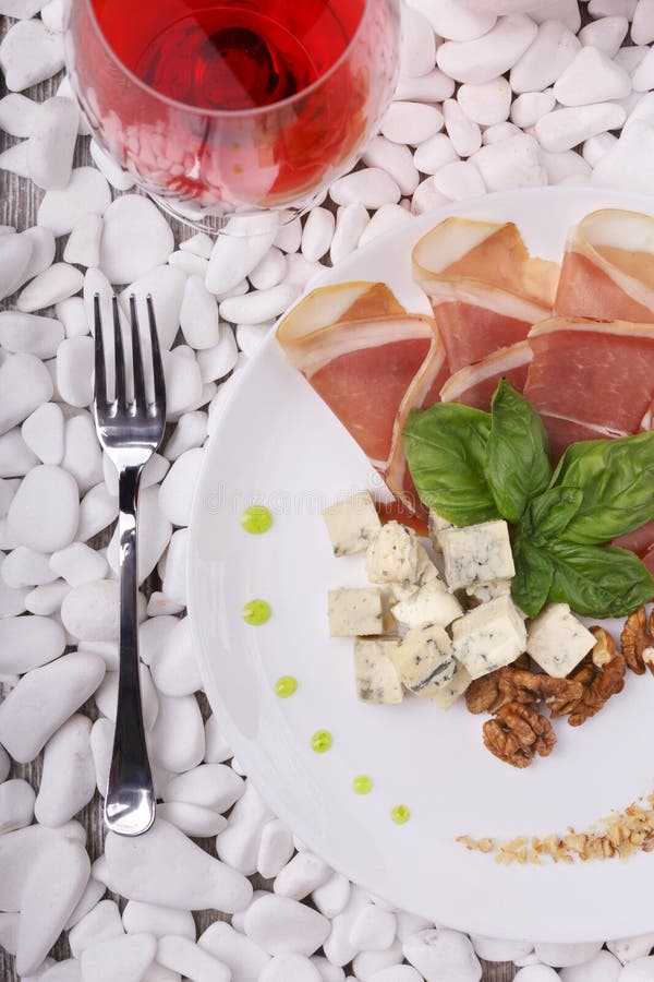Vue supérieure d'un plat blanc complètement de balyk, fromage et basilic et un verre à vin Épicerie fine sur les pierres blanches photo libre de droits Vue supérieure d'un plat blanc complètement de balyk, fromage et basilic et un verre à vin Épicerie fine sur les pierres blanches photo libre de droits