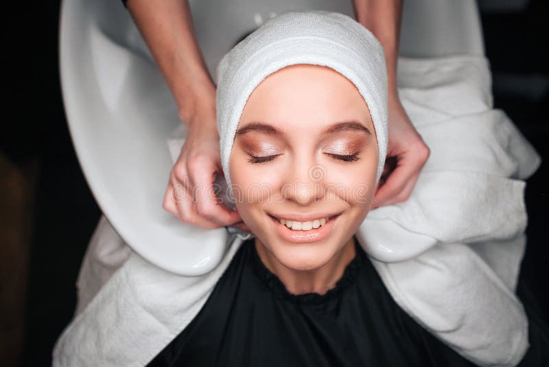 Vue supérieure de la belle femme de sourire satisfaite après le lavage professionnel et traitante des cheveux dans le salon de be photo stock Vue supérieure de la belle femme de sourire satisfaite après le lavage professionnel et traitante des cheveux dans le salon de be photo stock