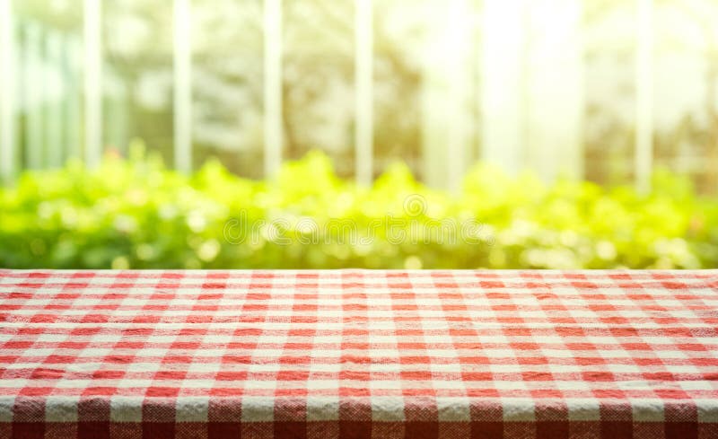 Red checkered tablecloth texture top view with abstract green from garden background.For montage product display or design key visual layout. Red checkered tablecloth texture top view with abstract green from garden background.For montage product display or design key visual layout.