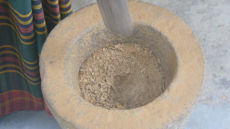 Vue supérieure des ingrédients de meulage d'homme indien méconnaissable dans un mortier et un pilon en pierre pour la préparation