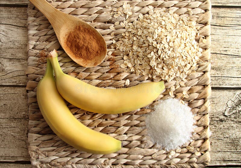 Vue supérieure des ingrédients des biscuits de régime - banane, farine d'avoine, sucre et cannelle sur un support fait de rotin photographie stock Vue supérieure des ingrédients des biscuits de régime - banane, farine d'avoine, sucre et cannelle sur un support fait de rotin photographie stock