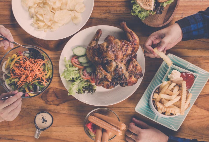 Top view.Group Of People Dining Concept.With Chicken roasting,salad,French fries on wooden table. Top view.Group Of People Dining Concept.With Chicken roasting,salad,French fries on wooden table