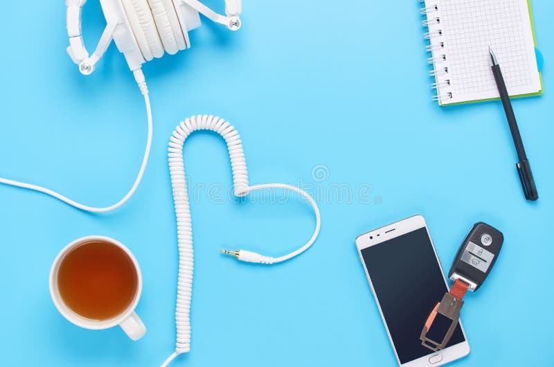 Vue supérieure sur des instruments sur le fond bleu, la composition des écouteurs blancs, le téléphone, le comprimé, le verre ave photographie stock Vue supérieure sur des instruments sur le fond bleu, la composition des écouteurs blancs, le téléphone, le comprimé, le verre ave photographie stock