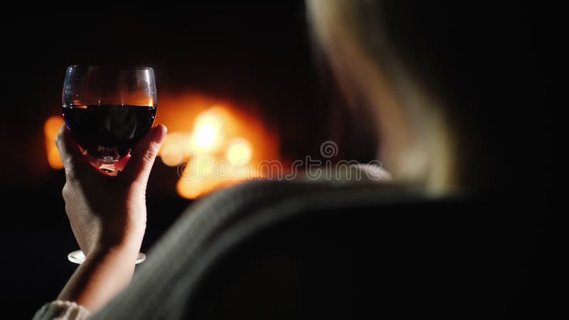 Vue sur l'épaule d'une femme avec un verre de vin au coin du feu banque de vidéos