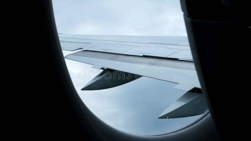 Vue sur une aile d'avion dans les nuages à travers un hublot. Arrière-plan nuageux du ciel orageux. Un avion par mauvais temps banque de vidéos
