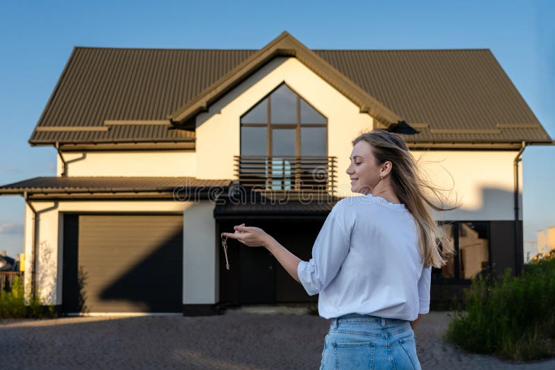 Vue sur une femme heureuse avec clés de maison devant une maison résidentielle. concept d'investissement immobilier. achat ou loca image libre de droits