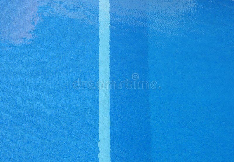 Vue verticale de plein cadre d'une piscine avec l'eau bleue ensoleillée et des ondulations avec une rayure sur les tuiles marquan photos libres de droits Vue verticale de plein cadre d'une piscine avec l'eau bleue ensoleillée et des ondulations avec une rayure sur les tuiles marquan photos libres de droits