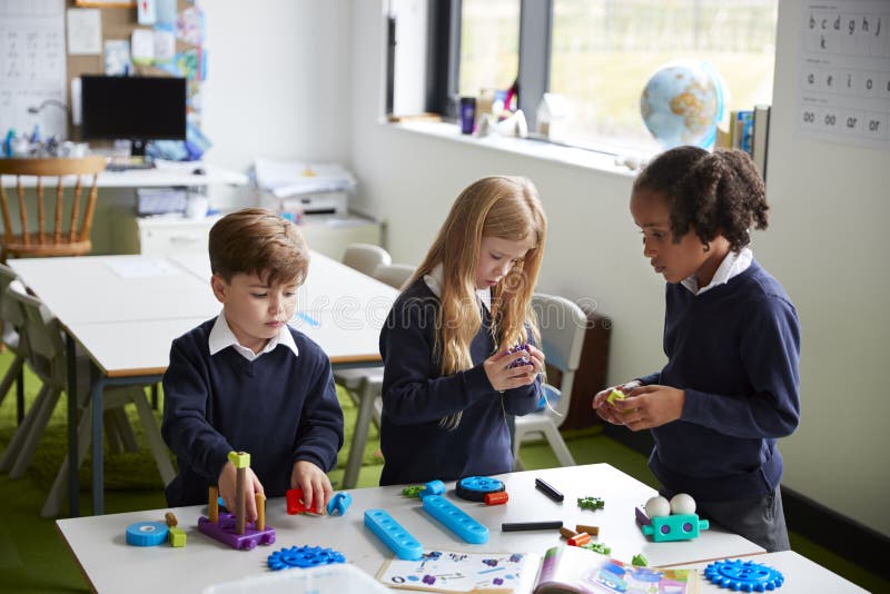 Vue élevée de trois enfants d'école primaire fonctionnant ensemble utilisant des blocs de construction dans une salle de classe images libres de droits Vue élevée de trois enfants d'école primaire fonctionnant ensemble utilisant des blocs de construction dans une salle de classe images libres de droits