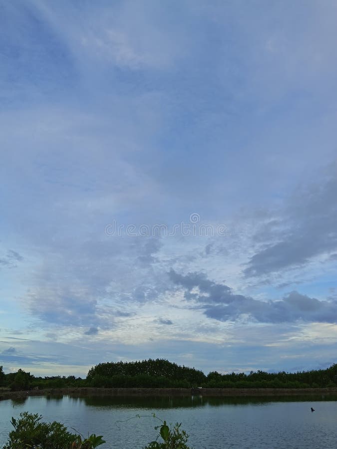 Vue époustouflante d'un plan d'eau calme en Indonésie qui se profile sous un ciel texturé. Idéal pour les sites Web image stock