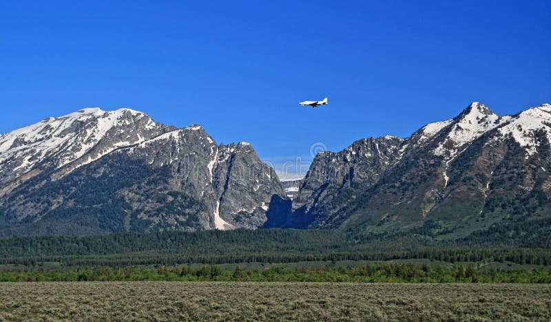 Lear Jet flying into Jackson Hole Airport next to the Grand Tetons Mountain Range in Wyoming USA. Lear Jet flying into Jackson Hole Airport next to the Grand Tetons Mountain Range in Wyoming USA