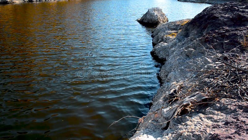 Vuil Water dat calmly op rotsachtig stroomt terwijl zand de overzeese kustbovenkant mening hengelde