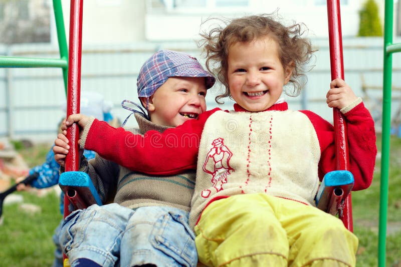 Dirty, happy little gypsy siblings on swings outdoor. Dirty, happy little gypsy siblings on swings outdoor