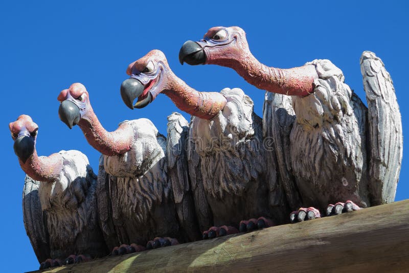 Sculpture of nasty vultures sitting on a plank and watch