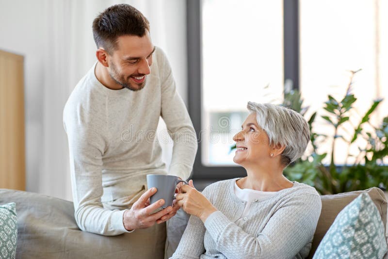 Vuxen son som hemma kommer med kaffe till den höga modern arkivbilder Vuxen son som hemma kommer med kaffe till den höga modern arkivbilder