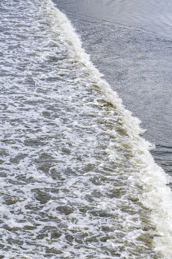 Vy en mjuk våg som bryter på en sandstrand och skapar en vacker textur av havsskum och våt sand royaltyfri bild