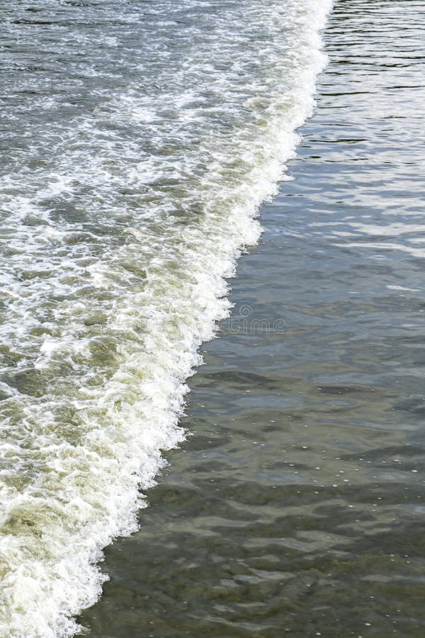 Vy en mjuk våg som bryter på en sandstrand och skapar en vacker textur av havsskum och våt sand fotografering för bildbyråer