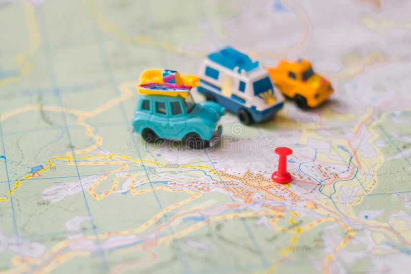 Several toy cars stand on a tourist map in a place marked with a pushpin. Trailer bus and jeep is in the tourist parking lot. Selective focus. Geographic concept of vacation travel. Several toy cars stand on a tourist map in a place marked with a pushpin. Trailer bus and jeep is in the tourist parking lot. Selective focus. Geographic concept of vacation travel