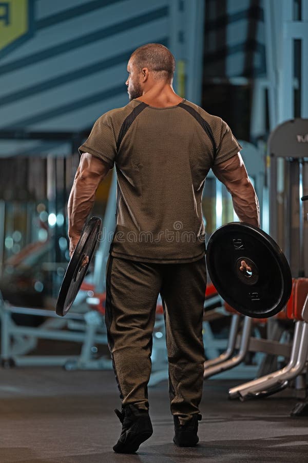 Väggvikter för manliga idrottare på ett gym under kvällsworkout med fokus på styrkeutbildning och förbättrad prestanda fotografering för bildbyråer