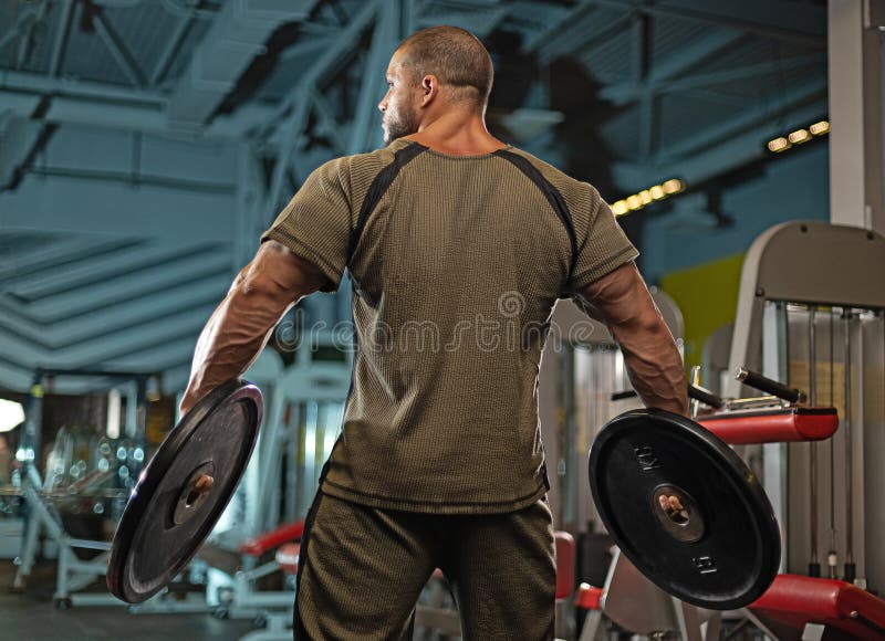 Väggvikter för manliga idrottare på gymmet under en intensiv träningssession för att öka styrka och lämplighet arkivbild