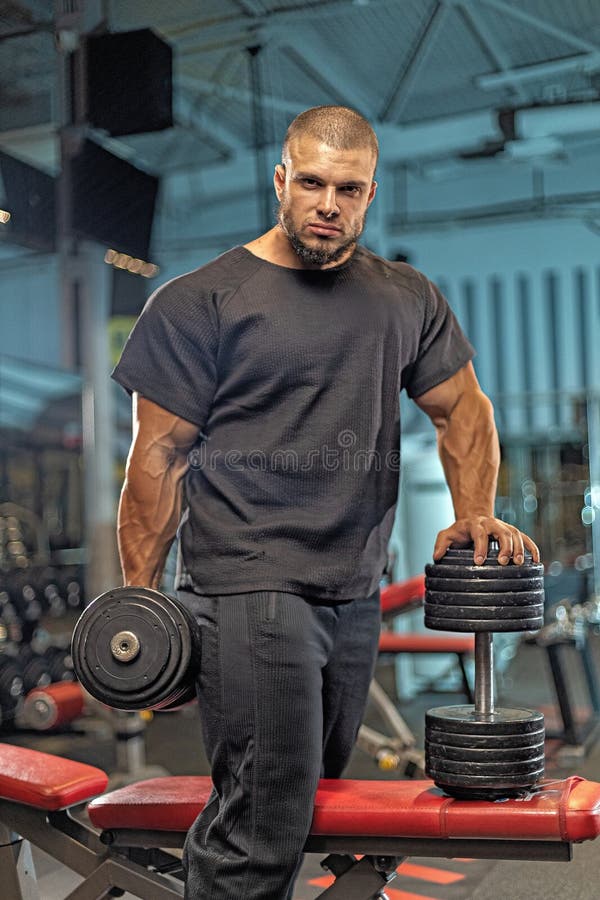 Väggvikter för manliga idrottsutövare på gymmet under en träningssession för styrkeuppbyggnad och förbättring av lämpligheten arkivbilder